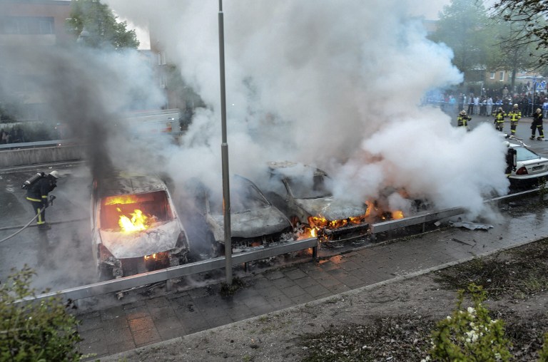 Firemen extinguish burning cars in the Stockholm suburb of Rinkeby after youths rioted in several different suburbs around Stockholm, Sweden for a fourth consecutive night on May 23, 2013. In the suburb of Husby, where the riots began on Sunday in response to the fatal police shooting of a 69-year-old machete-wielding man, 80 percent of residents are immigrants and the unrest has highlighted Sweden's failure to integrate swathes of its immigrant population, but in this small, consensus-driven country, there was little agreement on how to solve the problem. AFP PHOTO /SCANPIX SWEDEN/ FREDRIK SANDBERG SWEDEN OUT