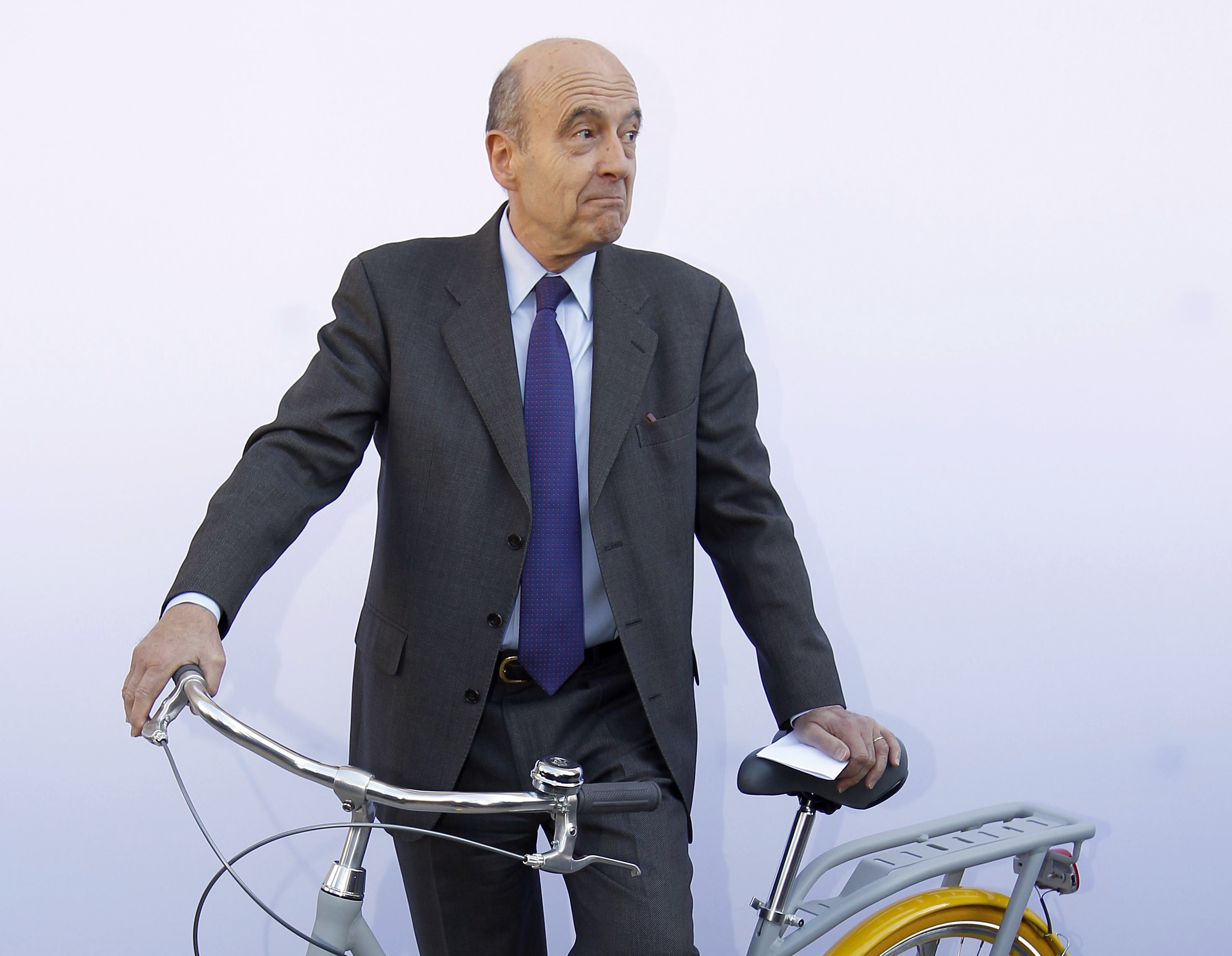 Alain Juppe, Mayor of Bordeaux, poses with the "Pibal" public bicycle designed by French designer Philippe Starck during a presentation at the Bordeaux city hall February 19, 2013. The hybrid bicycle, which will be available to the public from September 2013, has a central platform allowing the rider to push it like a scooter during heavy traffic, and has fluorescent tyres for security at night. REUTERS/Regis Duvignau (FRANCE - Tags: BUSINESS SOCIETY)