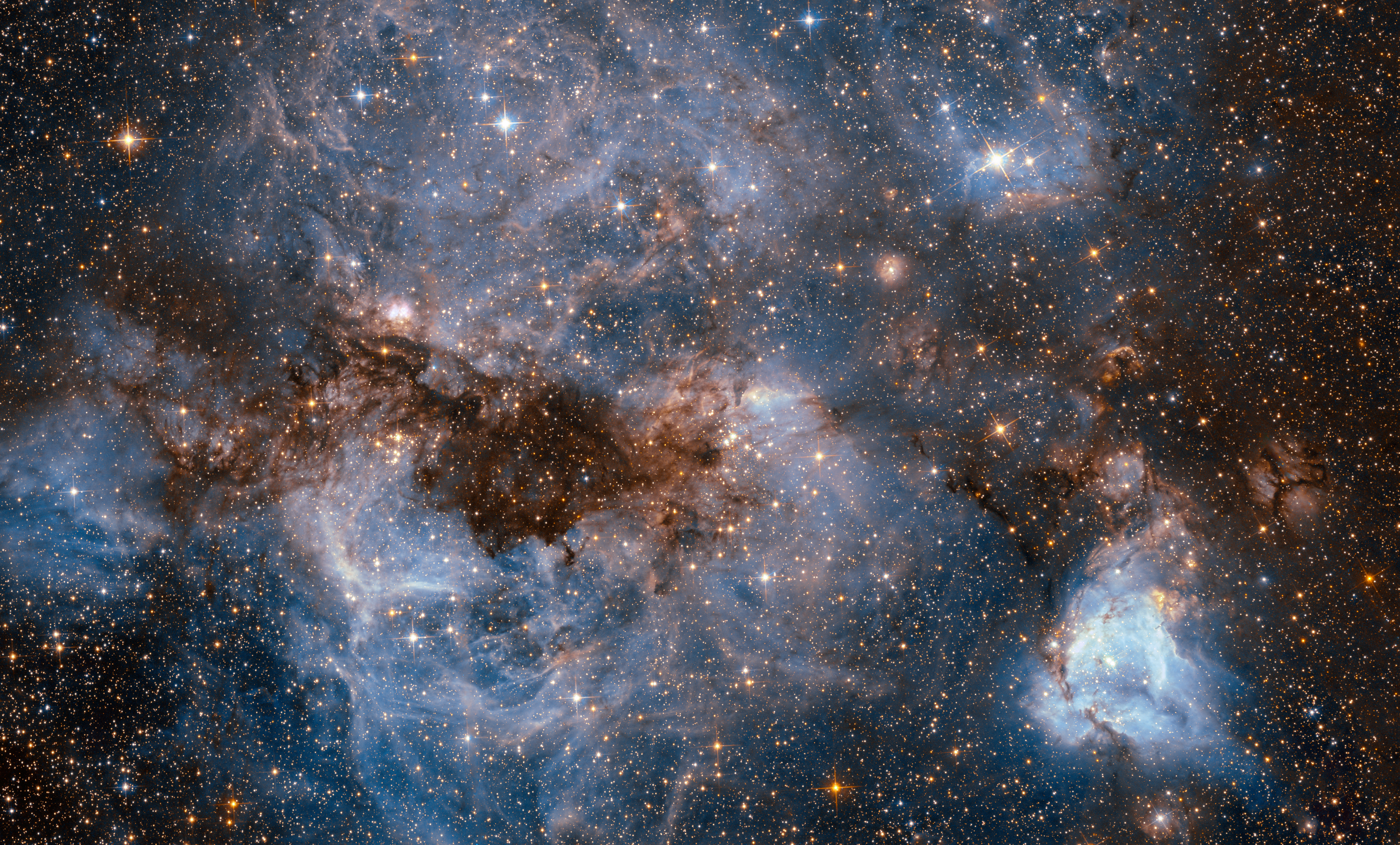 This shot from the NASA/ESA Hubble Space Telescope shows a maelstrom of glowing gas and dark dust within one of the Milky Way’s satellite galaxies, the Large Magellanic Cloud (LMC). This stormy scene shows a stellar nursery known as N159, an HII region over 150 light-years across. N159 contains many hot young stars. These stars are emitting intense ultraviolet light, which causes nearby hydrogen gas to glow, and torrential stellar winds, which are carving out ridges, arcs, and filaments from the surrounding material. At the heart of this cosmic cloud lies the Papillon Nebula, a butterfly-shaped region of nebulosity. This small, dense object is classified as a High-Excitation Blob, and is thought to be tightly linked to the early stages of massive star formation. N159 is located over 160 000 light-years away. It resides just south of the Tarantula Nebula (heic1402), another massive star-forming complex within the LMC. It was previously imaged by Hubble’s Wide Field Planetary Camera 2, which also resolved the Papillon Nebula for the first time.